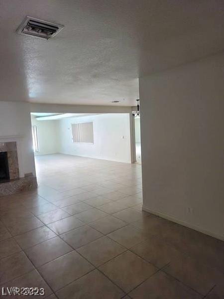 unfurnished room with a high end fireplace, visible vents, and a textured ceiling