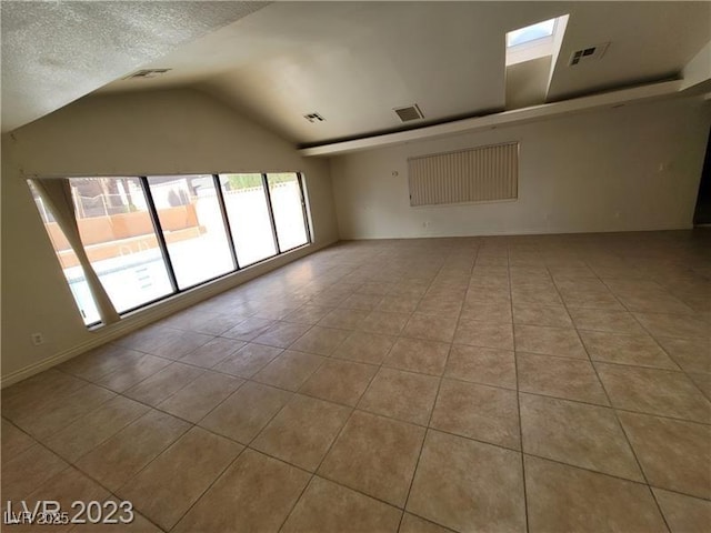 unfurnished room featuring lofted ceiling with skylight, visible vents, a textured ceiling, and tile patterned floors