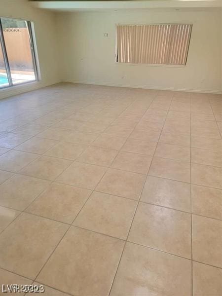 unfurnished room with light tile patterned floors and baseboards