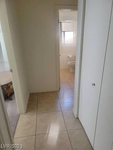 corridor with light tile patterned floors and baseboards