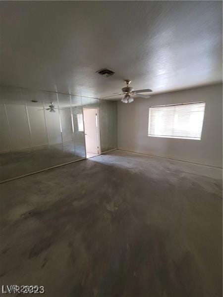 interior space with a ceiling fan, visible vents, and concrete floors