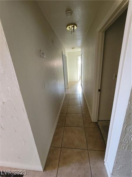 corridor with light tile patterned floors and baseboards