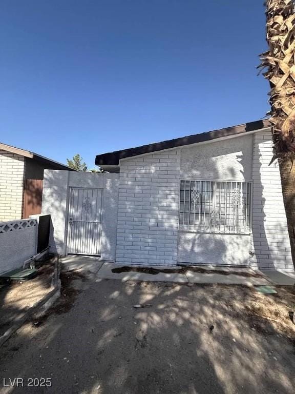 view of side of property with brick siding and a gate