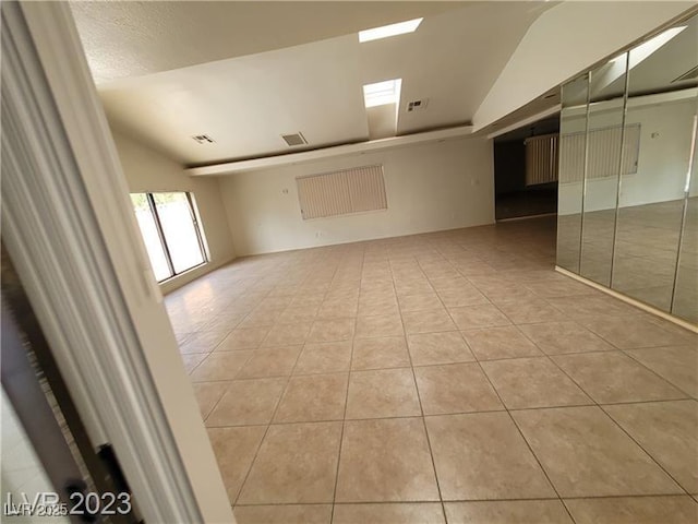 empty room with a skylight, visible vents, and light tile patterned flooring