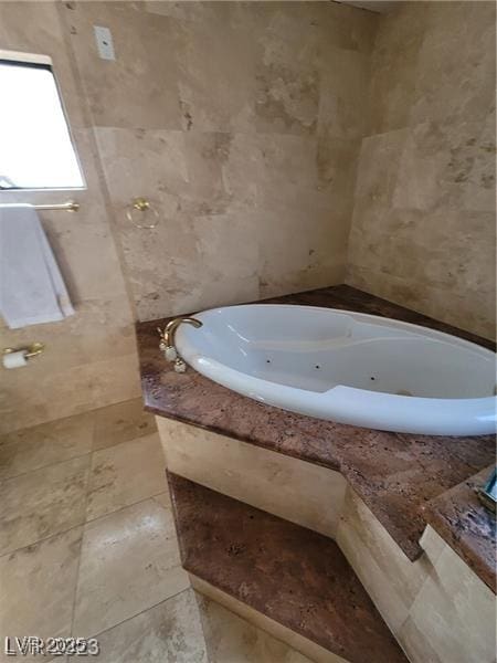 bathroom with a whirlpool tub and tile walls