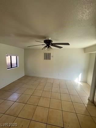 empty room featuring light tile patterned floors, a textured ceiling, visible vents, and a ceiling fan