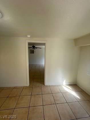 spare room with ceiling fan, baseboards, and light tile patterned floors