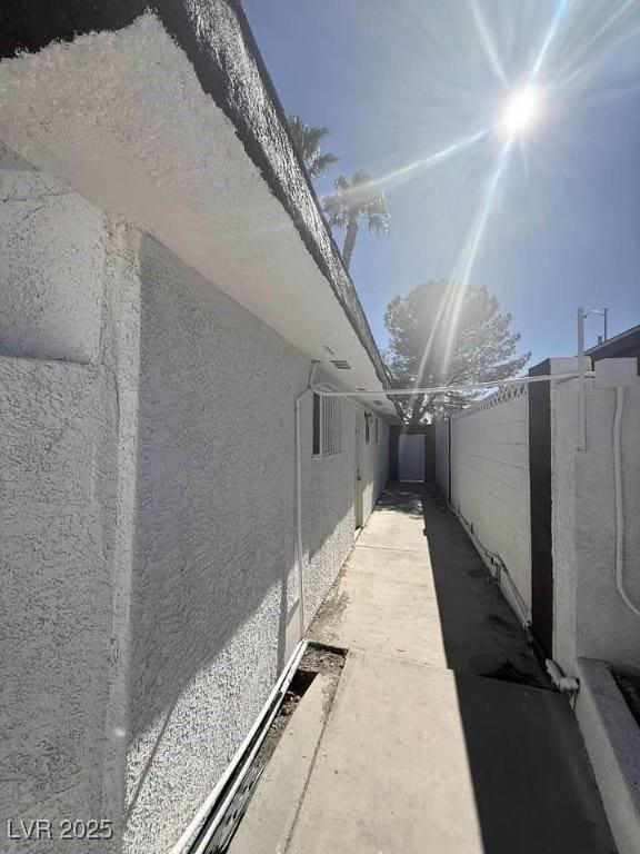 view of side of home with fence and stucco siding