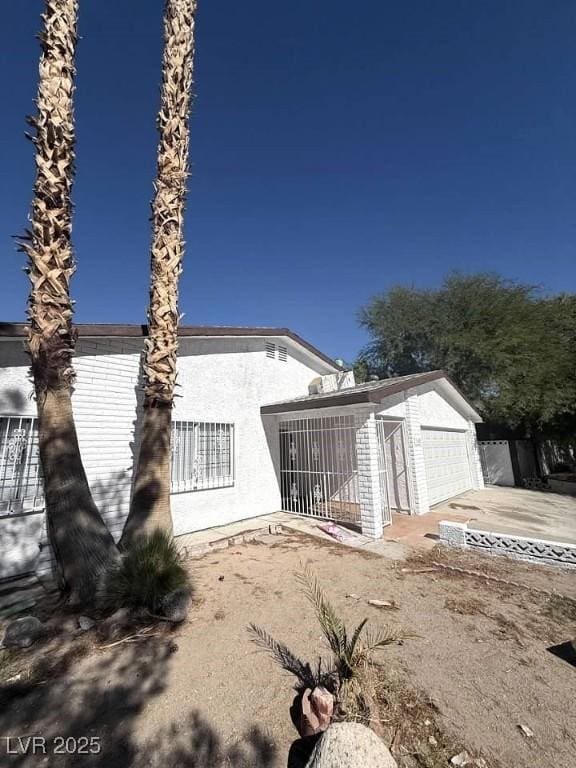 back of property with driveway and stucco siding