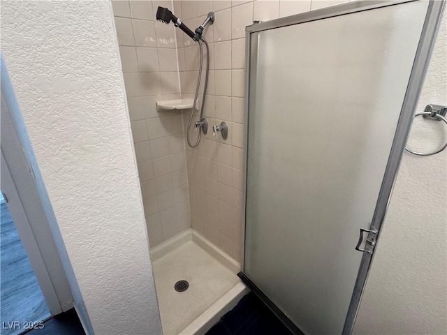 bathroom featuring a shower stall and a textured wall