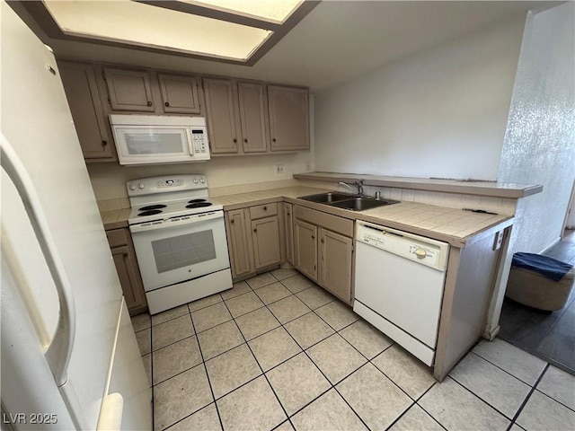 kitchen featuring white appliances, light tile patterned floors, tile counters, a peninsula, and a sink