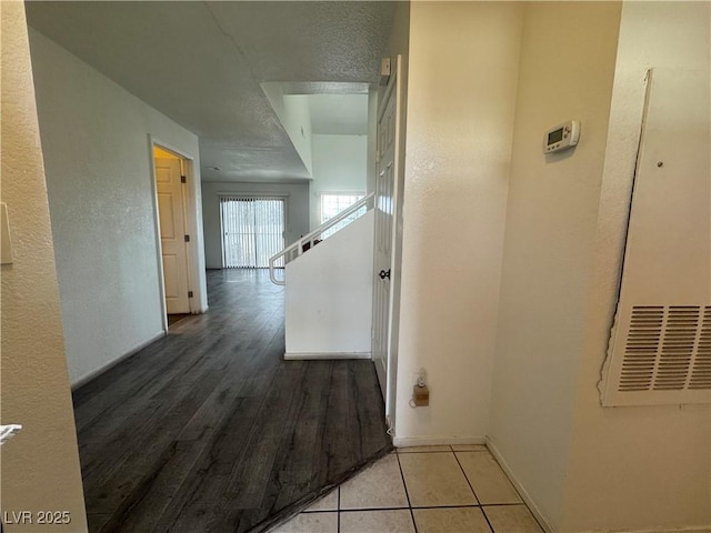 hallway with a textured wall, wood finished floors, and baseboards