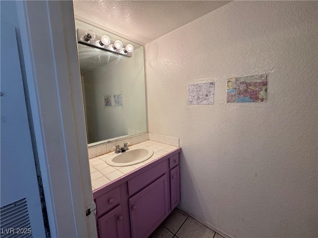 bathroom featuring a textured wall, vanity, a textured ceiling, and tile patterned floors