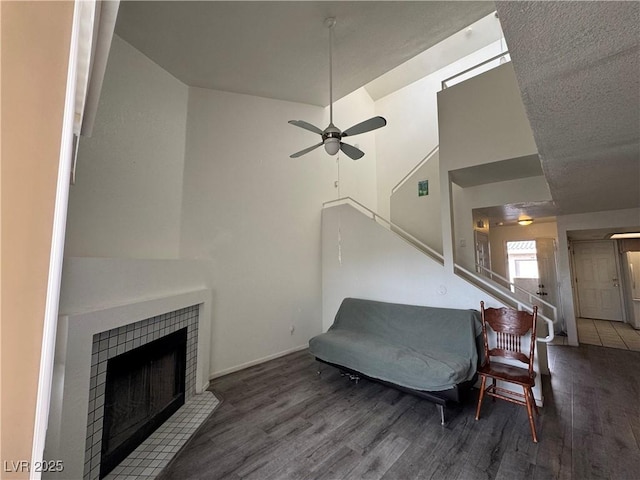 living area featuring a tiled fireplace, wood finished floors, and a ceiling fan