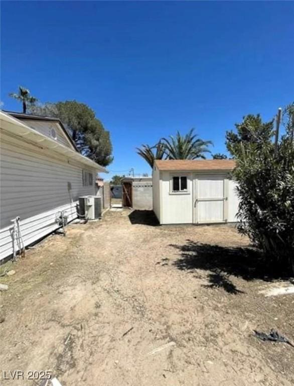 view of yard featuring an outbuilding, central air condition unit, fence, and a storage unit