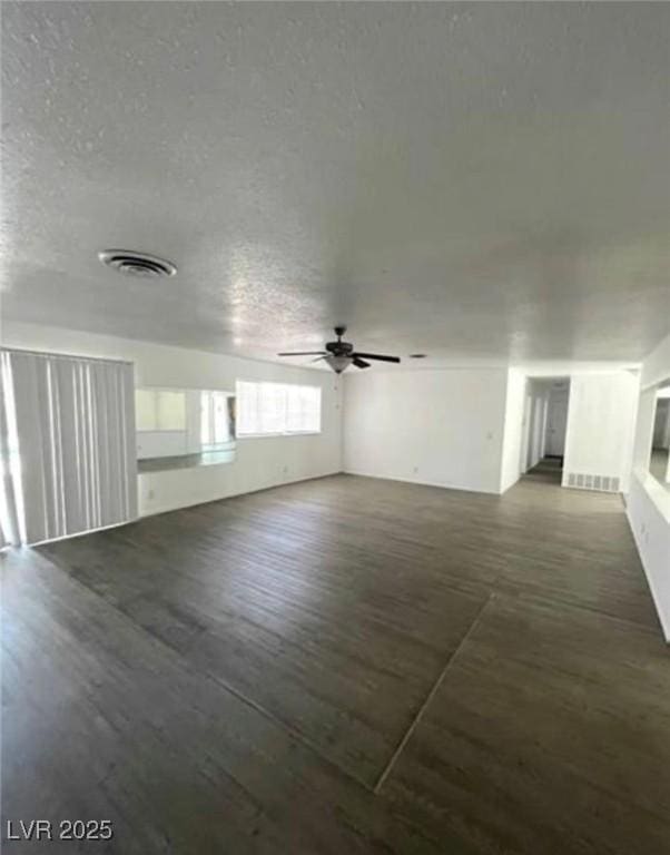 empty room featuring a textured ceiling, wood finished floors, and visible vents