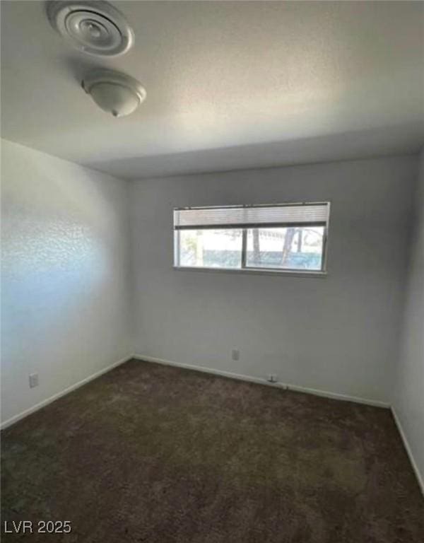 unfurnished room with dark colored carpet and baseboards