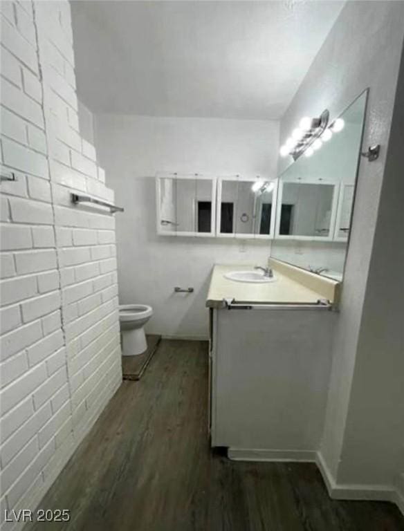 bathroom with toilet, wood finished floors, and vanity