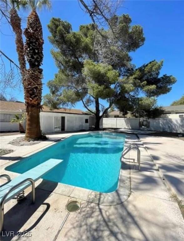 view of swimming pool with fence, a diving board, a fenced in pool, and a patio