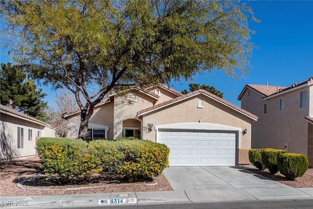 view of front of house featuring a garage, concrete driveway, a tile roof, and stucco siding