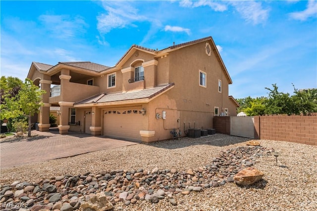 view of front of property featuring stucco siding, central AC unit, fence, a garage, and driveway