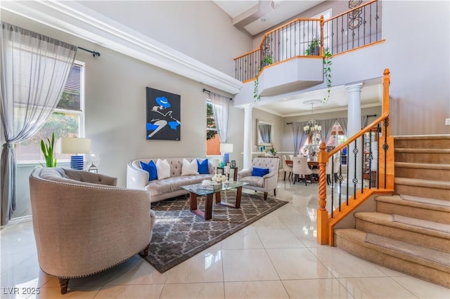 living area featuring a notable chandelier, stairway, a high ceiling, tile patterned flooring, and ornate columns