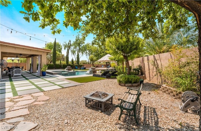 view of yard with a pool with connected hot tub, a ceiling fan, a patio area, a fenced backyard, and a fire pit