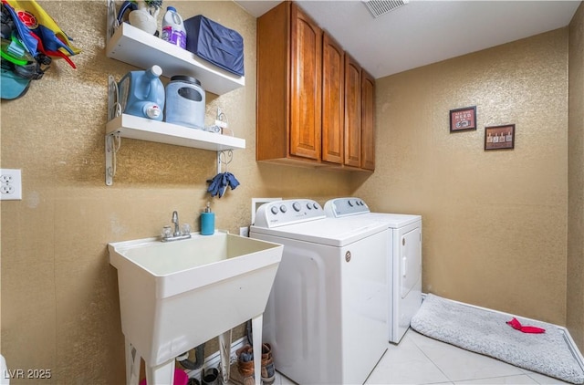 washroom with cabinet space, visible vents, a textured wall, separate washer and dryer, and a sink