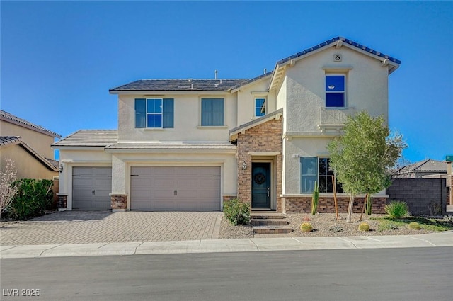 view of front of house with an attached garage, solar panels, stone siding, decorative driveway, and stucco siding