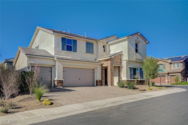 view of front facade featuring decorative driveway, an attached garage, and stucco siding