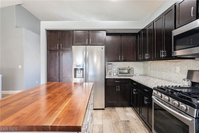 kitchen with light wood-style floors, wooden counters, stainless steel appliances, and backsplash