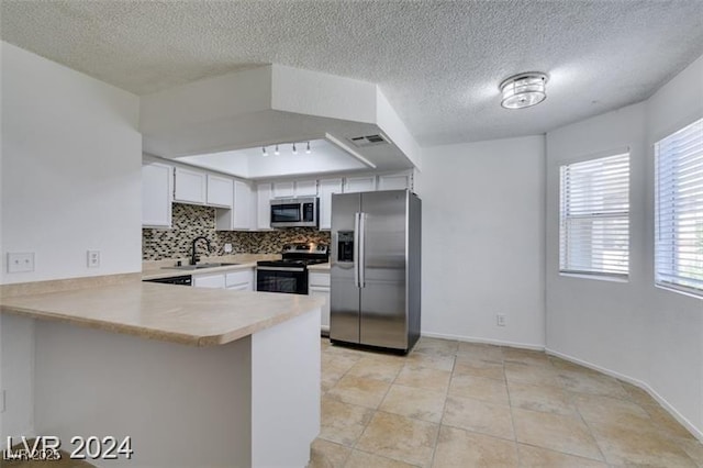 kitchen with light countertops, backsplash, appliances with stainless steel finishes, a sink, and a peninsula