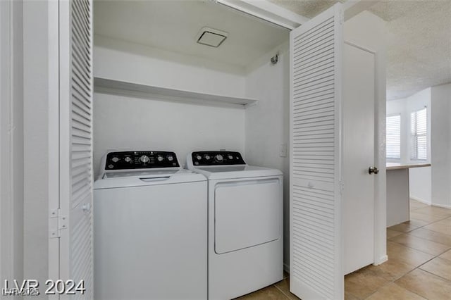 washroom featuring light tile patterned floors, washing machine and dryer, and a textured ceiling