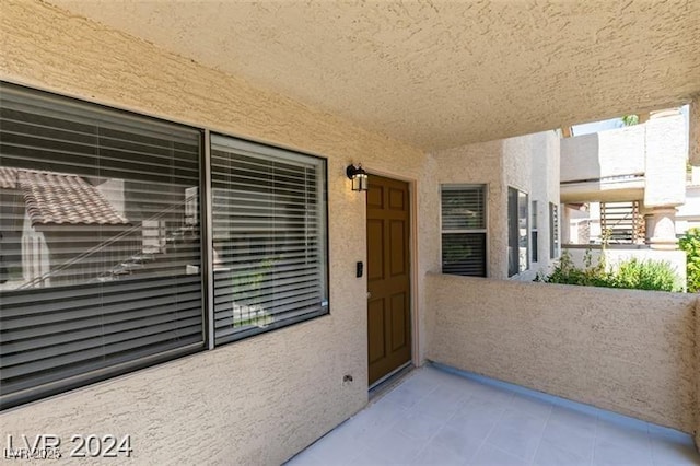 view of exterior entry with a balcony and stucco siding