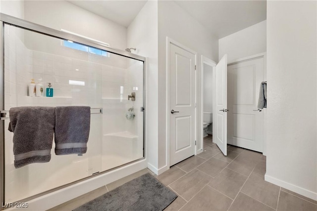 full bath with baseboards, a shower stall, toilet, and tile patterned floors