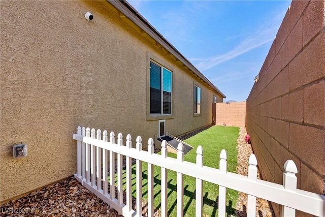 view of side of property with a fenced backyard and stucco siding