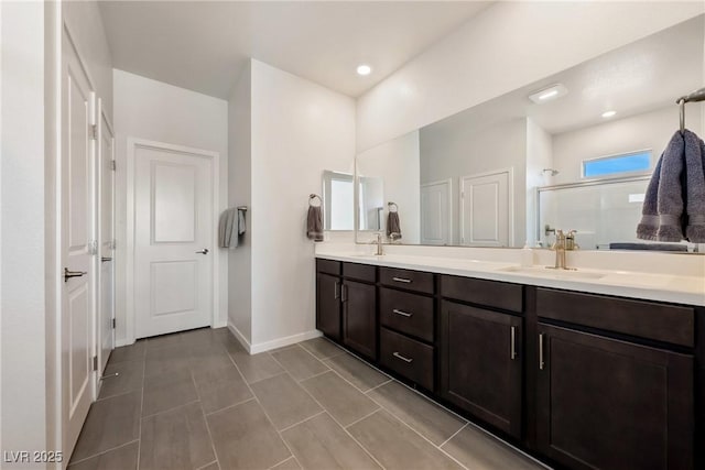 full bathroom featuring double vanity, baseboards, an enclosed shower, a sink, and recessed lighting