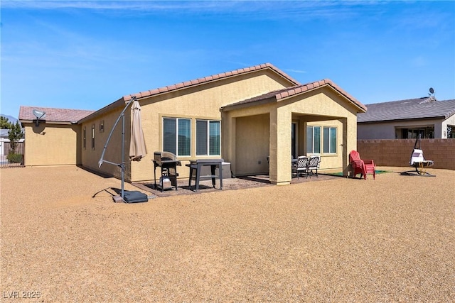 rear view of house featuring a patio area, a tile roof, fence, and stucco siding