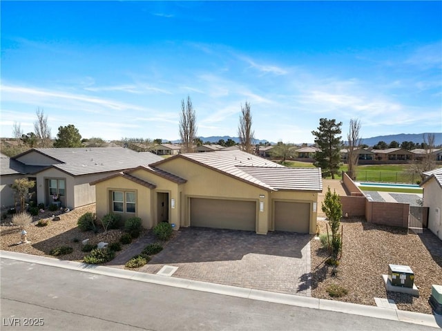 view of front of house featuring a garage, fence, decorative driveway, a residential view, and stucco siding