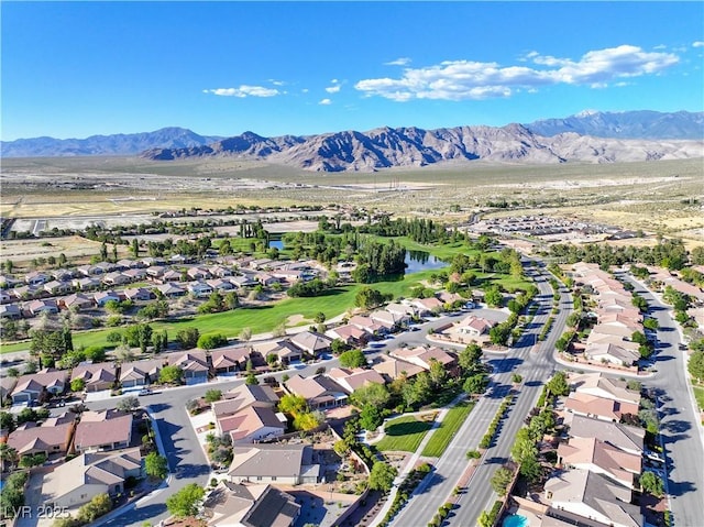 drone / aerial view featuring view of golf course, a water and mountain view, and a residential view