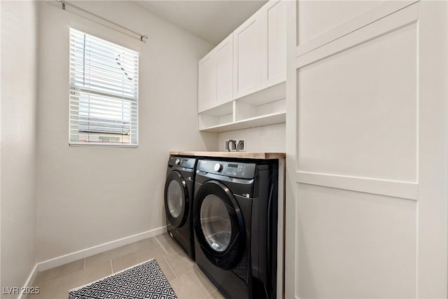 clothes washing area with washing machine and dryer, baseboards, and light tile patterned floors