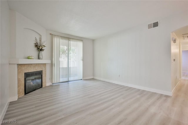 unfurnished living room with visible vents, a fireplace, baseboards, and wood finished floors