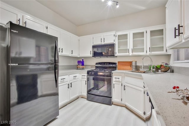 kitchen featuring white cabinetry, black appliances, glass insert cabinets, and a sink