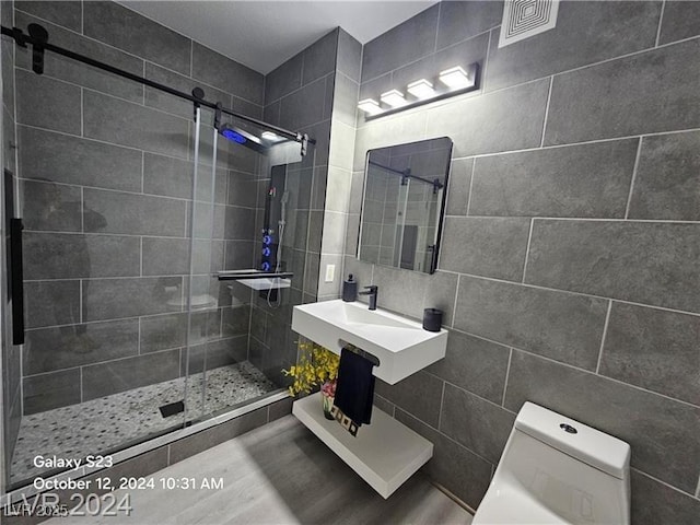 bathroom with visible vents, toilet, a stall shower, a sink, and tile walls