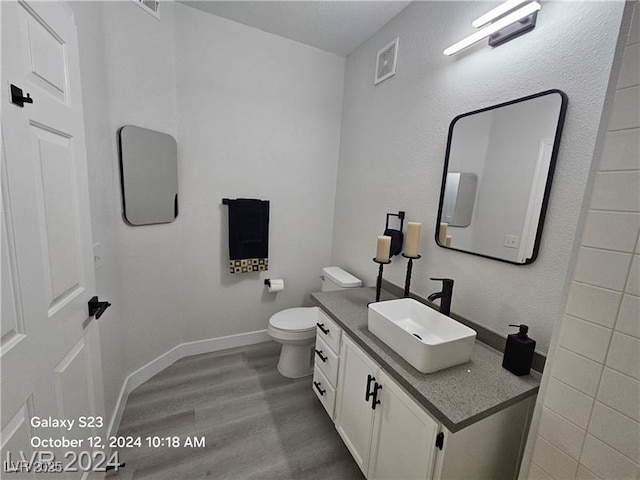 bathroom with visible vents, toilet, wood finished floors, baseboards, and vanity