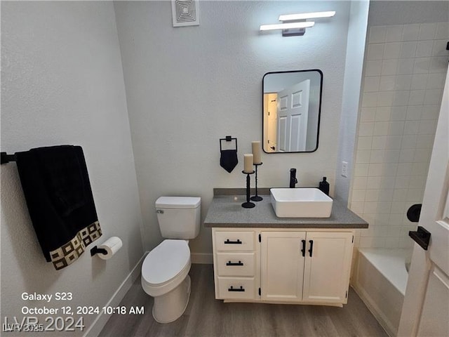 bathroom with toilet, wood finished floors, vanity, baseboards, and shower / bathtub combination