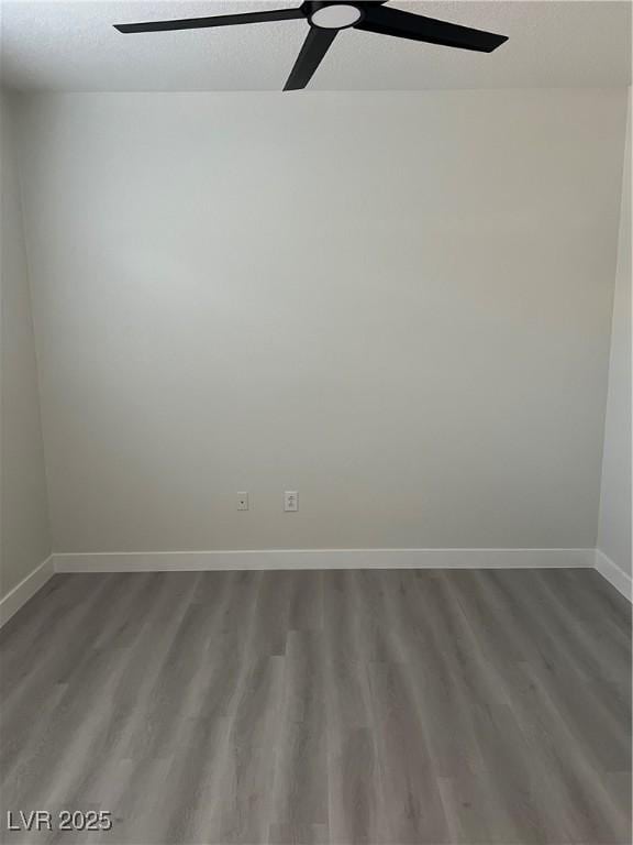 unfurnished room with baseboards, wood finished floors, and a ceiling fan