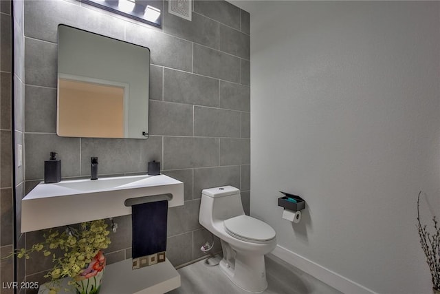 bathroom featuring visible vents, toilet, and tile walls