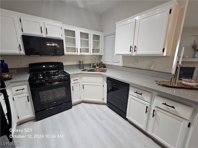 kitchen featuring white cabinetry, black appliances, and a sink