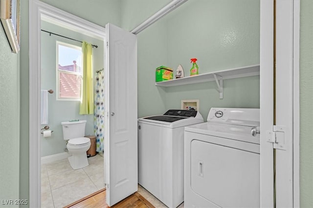 washroom featuring laundry area, light tile patterned floors, baseboards, and washer and clothes dryer